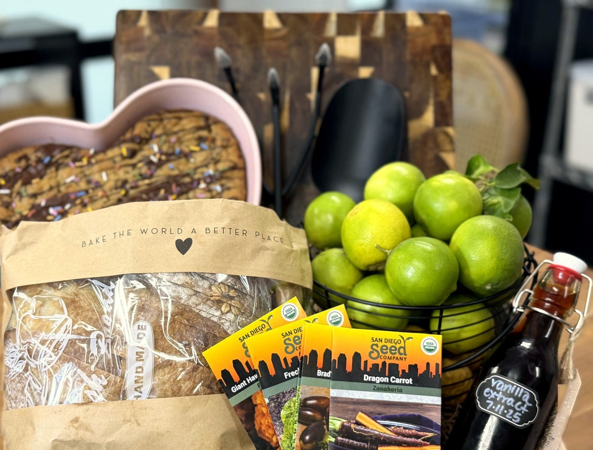 A gift basket from Susie's kitchen with a heart cookie, sourdough bread, limes, seed packets and homemade vanilla extract